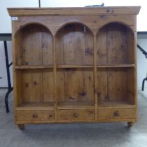 An early 20thC rustically constructed pine hanging unit with two open shelves, over a trio of inline