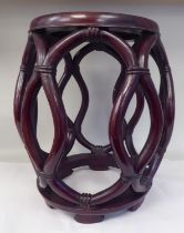 A 20thC Oriental mahogany framed open barrel design stool with simulated bamboo supports