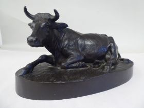 A cast and patinated bronze model, a recumbent cow, on an oval base  bears an indistinctly impressed