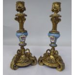 A pair of late 19thC Continental decoratively cast gilt metal and painted porcelain candlesticks