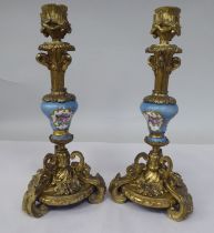 A pair of late 19thC Continental decoratively cast gilt metal and painted porcelain candlesticks