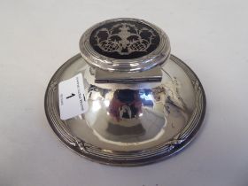 An Edwardian loaded silver capstan design inkwell with cast ribbon tied ornament and a