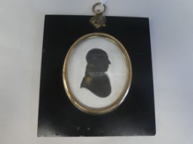 An 18thC oval profile head and shoulders portrait miniature, part gilded silhouette, featuring a