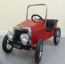 A painted model pedal car, in the manner of a veteran vehicle with red livery and spoked rubber