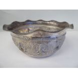 An Asian silver coloured metal bowl with a cut, flared, wavy edged, everted rim, cast and chased