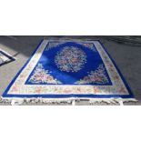 A Chinese washed woollen carpet, decorated with a central floral bouquet motif, bordered by