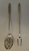 A Liberty & Co silver coloured metal olive spoon and fork, on decoratively cast handles