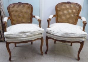 A pair of modern French style, moulded and carved beech framed open arm chairs, each having a double