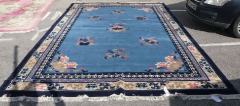 A Chinese washed woollen carpet, decorated with stylised ribbon and floral designs, on a mainly