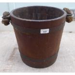 An early 20thC rustically constructed coopered oak bucket with brass bands and a stitched hide