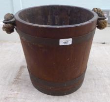 An early 20thC rustically constructed coopered oak bucket with brass bands and a stitched hide