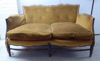 An early 20thC stained beech showwood framed two person settee, upholstered in old gold/orange
