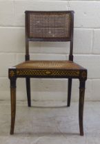 A Regency gilded black lacquered and overpainted hall chair with a caned back panel and seat, raised