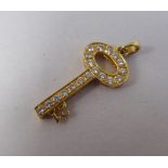 An 18ct gold bracelet charm, fashioned as a key, the teeth shaped as a '21' set with diamonds