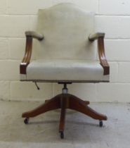 A 20thC mahogany showwood framed desk chair with open arms, stud upholstered in olive coloured hide,