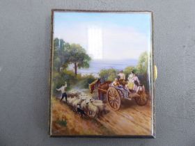 A gold plated metal and coloured enamelled folding cigarette case, featuring a shepherd with a flock