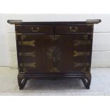 A 20thC Chinese hardwood side cabinet with two drawers, over two doors with rivetted brass mounts,
