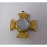 A yellow metal cross pendant, set with a central gemstone