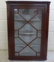 A late 19thC mahogany corner cabinet with a glazed door, on a plinth  39"h  28"w