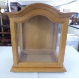 A 20thC light oak display cabinet, fashioned as a granddaughter clock hood, on a plinth  17"h  14.