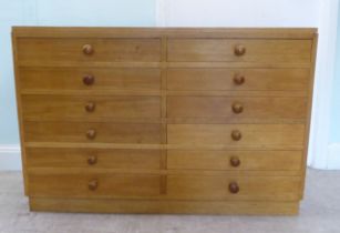 A mid 20thC fruitwood collector's chest with two banks of six drawers, some with dividers, on a