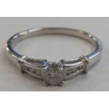 A 9ct white gold solitaire ring, set with a raised central diamond, flanked by diamond shoulders