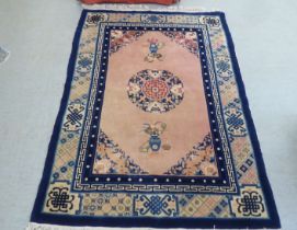 A Chinese rug, decorated with vase motifs, on a blue and peach ground  72" x 48"