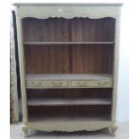 A modern French design, cream painted bookcase with three open shelves and two drawers, raised on