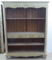 A modern French design, cream painted bookcase with three open shelves and two drawers, raised on