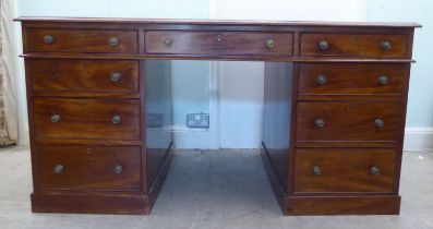 A late Victorian mahogany partner's desk, the top set with a tooled green hide scriber, raised on