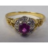 An 18ct gold cluster ring, set with a central round cut ruby, surrounded by diamonds