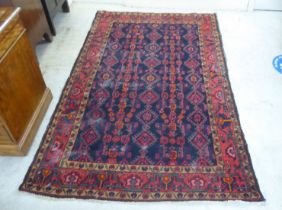 A Persian rug, decorated with repeating stylised designs, on a multi-coloured ground  55" x 88"