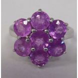 A silver cluster ring, set with seven round cut pink sapphires