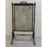 An early 20thC black lacquered, wooden firescreen, the central glazed plate supported by a fluted
