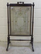 An early 20thC black lacquered, wooden firescreen, the central glazed plate supported by a fluted