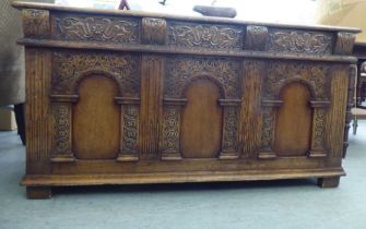 A Titchmarsh & Goodwin Old English style oak coffer with straight sides, a hinged lid and carved