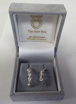 A pair of white metal half-hoop earrings, each set with six diamonds  cased