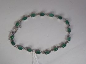 A silver bracelet, set with oval cut emeralds