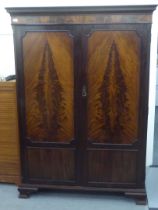 An early 20thC figured mahogany veneered wardrobe, having a moulded cornice, over a pair of panelled