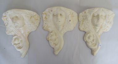 Three 20thC cream painted cast iron wall plaques, fashioned as busts  12"h