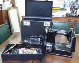 An electrically powered Singer sewing machine  boxed with accessories