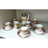 A Noritake porcelain coffee set, decorated with a sunset landscape with gilt trim and banding