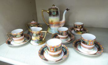 A Noritake porcelain coffee set, decorated with a sunset landscape with gilt trim and banding