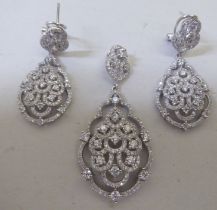 A pair of silver earrings of stepped teardrop design, set with cubic zirconia; and a matching