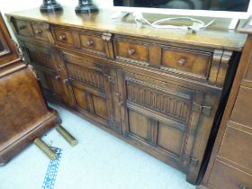 A 20thC Old English style oak sideboard with three frieze drawers, over three panelled doors, raised