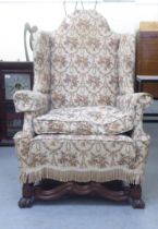 A late 19thC walnut framed tapestry upholstered wingback armchair, raised on paw feet