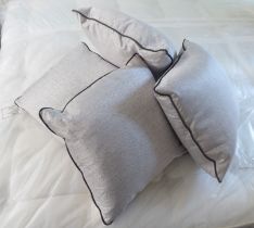 A set of four silver/cream coloured scatter cushions with brown piping