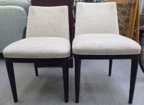 A pair of modern Wychwood Design side chairs, upholstered in biscuit coloured fabric, raised on