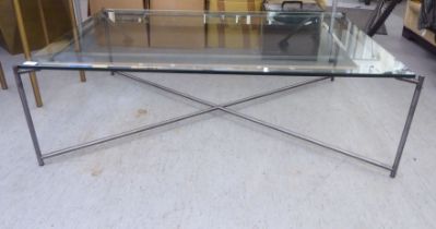 A modern tubular iron framed coffee table with a plate glass top  16"h  49"w
