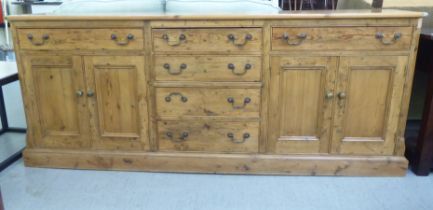 A reproduction of a 19thC waxed pine dresser, comprising an arrangement of doors and shallow drawers